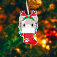 Load image into Gallery viewer, Christmas ornament with a cat in a stocking and reindeer antlers against a blurred Christmas tree background.
