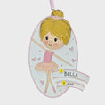 Load image into Gallery viewer, Personalized ballet girl Christmas ornament featuring a cute ballerina character in a pink tutu dress with heart details, customizable name area on the front banner and customizable year area below, glossy finish with raised 3D front details and flat 2D back, white hanging ribbon, displayed on a snowy holiday background with pine branches and festive decorations.