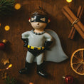 Load image into Gallery viewer, Personalized superhero boy Christmas ornament featuring a mask, cape and custom name. Cute holiday decor for boys, perfect for Christmas trees and gift-giving. Add name and year to create a unique keepsake. Display photos are AI-generated; please check the first image for the original product.