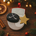 Load image into Gallery viewer, Hockey-themed Christmas ornament with a star on a wooden surface with festive decorations.