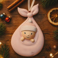Load image into Gallery viewer, Decorative baby ornament in a pink blanket on a wooden surface with Christmas decorations.