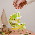 Load image into Gallery viewer, Decorative fish ornament with measuring tape around it, held by a hand against a neutral background.