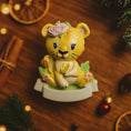 Load image into Gallery viewer, Personalized baby lion Christmas ornament featuring a sweet yellow lion cub wearing a floral crown and holding a small leaf. The bottom banner can be customized with name and year, creating a unique keepsake for a newborn or toddler. Designed in warm yellow and soft pastel tones, this resin baby Christmas ornament is perfect for celebrating Baby’s First Christmas or adding a personalized jungle themed touch to your holiday tree.