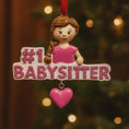 Load image into Gallery viewer, Personalized Babysitter Christmas ornament featuring a detailed raised 3D front design with glitter pink lettering and a charming girl figure. Custom name is added on the shirt and year is written on the hanging heart charm. Bright pink and white holiday colors stand out beautifully on the tree. Flat 2D back for easy hanging. Perfect keepsake gift for babysitter appreciation, nanny thank you present, childcare provider Christmas decor.