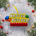 Load image into Gallery viewer, Personalized Master Builder Christmas ornament featuring a raised 3D front with colorful building block design and bold lettering. The ornament has a flat 2D back for easy hanging and durability. Bright primary colors and playful block details make it perfect for kids who love building toys. Personalization includes name and year, added by hand, making it a fun and meaningful holiday keepsake for children and young builders.