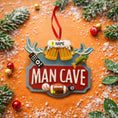 Load image into Gallery viewer, Man cave themed personalized ornament featuring a bold red Man Cave sign design with raised 3D details including beer mugs antlers sports icons and hobby elements. The ornament allows name personalization on the top area and year personalization at the bottom making it a fun and meaningful keepsake. Designed with a flat back for easy hanging this ornament is perfect for man cave decor Christmas trees or gift displays. Ideal for dads husbands boyfriends and anyone who loves their personal space traditions an