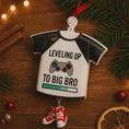 Load image into Gallery viewer, Decorative ornament shaped like a t-shirt with text and a gaming controller graphic, on a wooden surface with Christmas decorations.
