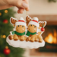 Load image into Gallery viewer, Two moose Christmas ornaments with Santa hats and scarves, held against a festive background.

