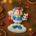Load image into Gallery viewer, Christmas ornament of a fox character holding a gift on a wooden surface with festive decorations.

