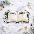 Load image into Gallery viewer, Personalized Holy Bible Christmas Ornament featuring an open scripture design with elegant “Holy Bible” lettering across the pages. The left page is customized with a name and the right page displays the year, creating a meaningful faith based keepsake. Surrounded by soft greenery and delicate flowers, this religious ornament is perfect for baptisms, baby dedications, first communions, or celebrating a Christ centered Christmas. A thoughtful spiritual gift for families who cherish their faith.
