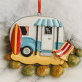 Load image into Gallery viewer, Decorative ornament of a camper with a surfboard and beach chair on a marble surface.
