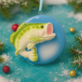 Load image into Gallery viewer, Decorative Bass fish ornament held by a hand with a blurred Christmas tree in the background
