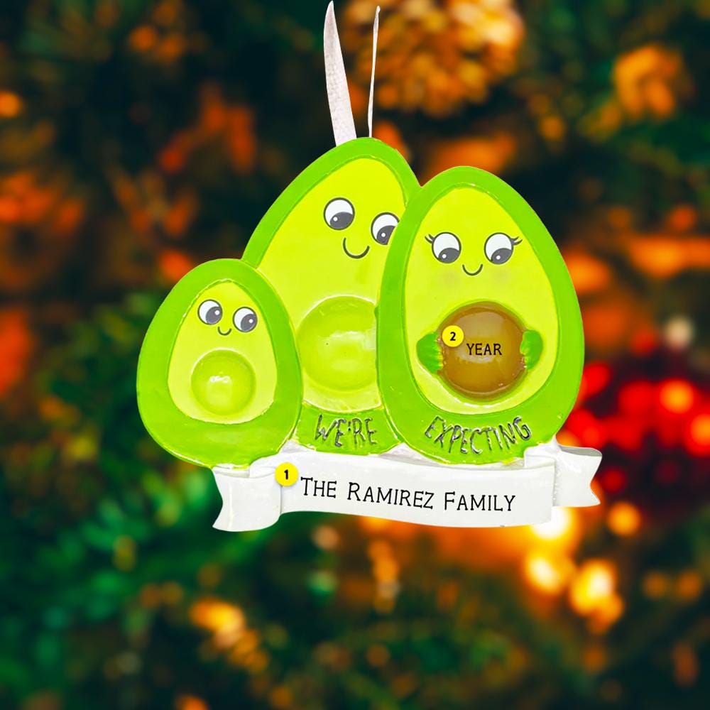 Avocado-themed pregnancy announcement decoration with 'We're Expecting' text on a blurred nature background.