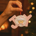 Load image into Gallery viewer, Decorative Christmas ornament shaped like a letter 'joy' with a baby face design, held by a hand against a blurred festive background.

