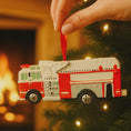 Load image into Gallery viewer, Fire truck ornament on a string with a warm, blurred background
