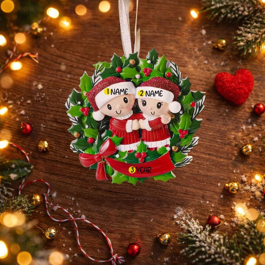 Personalized Christmas ornament with couple in a wreath on a wooden background with festive decorations.