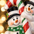 Load image into Gallery viewer, Two snowman figurines with candy cane hats against a blurred light background
