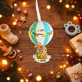 Load image into Gallery viewer, A personalized baby boy ornament featuring a cute bunny riding a pastel blue hot air balloon. Soft blue and white tones with gentle decorative details create a calm and cozy look. Handwritten personalization includes baby name and year. Mostly 2D ornament with raised 3D details on the front only, lightweight and easy to hang, perfect for baby first Christmas, nursery decor, and toddler keepsakes.
