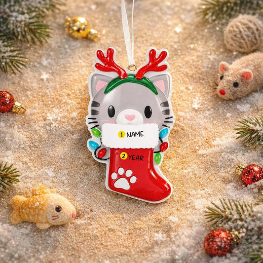 Christmas ornament with a cat in a stocking and reindeer antlers on a decorative background.