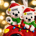 Load image into Gallery viewer, Personalized Christmas ornament featuring two polar bears wearing Santa hats riding in a red car decorated with colorful holiday lights. The ornament includes custom name personalization on each bear and a year displayed on the car. Designed with a detailed 3D raised front and smooth glossy finish, it is made for easy hanging on a Christmas tree. Perfect for festive holiday decor, couple ornaments, family keepsakes, and seasonal gift giving.
