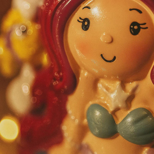 close lookupfigure of a mermaid with red hair and green tail on a blurred background