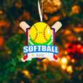 Load image into Gallery viewer, Personalized softball Christmas ornament featuring a yellow softball with stitched details and crossed bats design on a shield style background, customizable name area on the front banner and customizable year area on the softball, glossy finish with raised 3D front details and flat 2D back, white hanging ribbon, displayed on a snowy softball field themed holiday background with pine branches and festive decorations.

