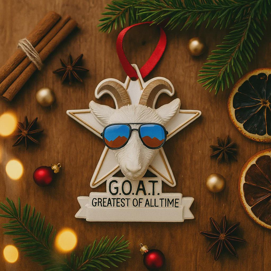 Decorative ornament with goat wearing sunglasses and 'G.O.A.T.' text on a wooden surface with festive items.