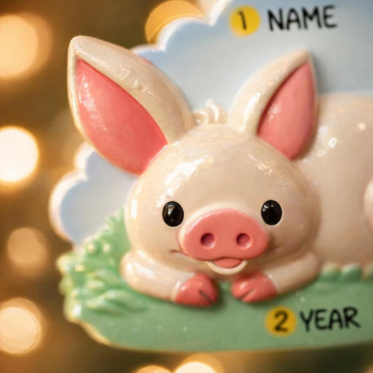 Cute pig figurine on a decorative card with 'NAME' and '2 YEAR' text, against a blurred golden background.