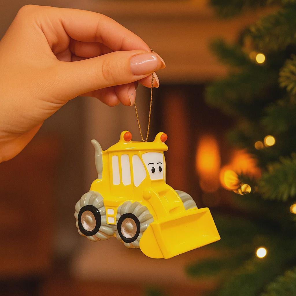 Yellow bulldozer ornament held by a hand with a Christmas tree in the background