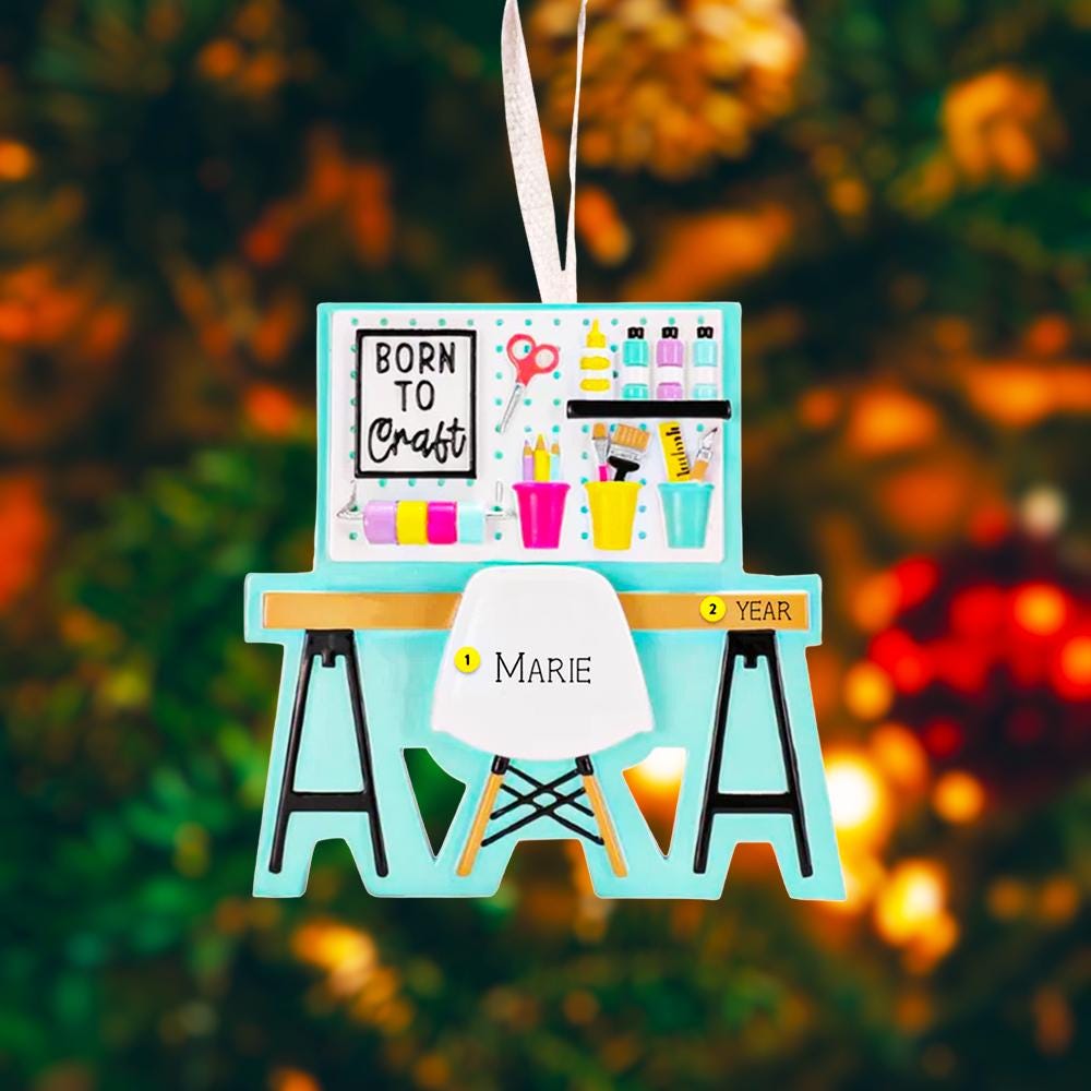 Born to Craft ornament featuring a creative desk scene with colorful craft supplies including scissors paint bottles brushes pencils and storage cups. The ornament showcases a playful crafting workspace design with a modern chair and desk setup. Made from durable resin with a detailed 3D front and flat 2D back for smooth hanging. Includes free handwritten personalization making it a perfect gift for crafters artists DIY lovers and creative kids. Ideal for Christmas trees craft rooms studios and handmade the