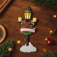 Load image into Gallery viewer, Decorative Christmas street lamp ornament on a wooden surface with festive decorations.
