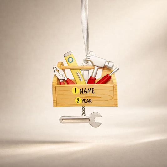 Personalized handyman ornament featuring a wooden style toolbox filled with tools including hammer wrench pliers and level. Custom name and year displayed on the front. Mostly 2D design with raised 3D tool details on the surface. Perfect Christmas ornament for handyman contractors mechanics and skilled trade workers.