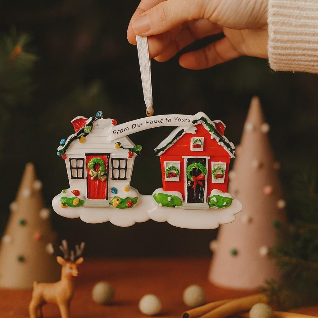 Decorative Christmas ornament shaped like two houses with a banner reading 'From Our House to Yours'.
