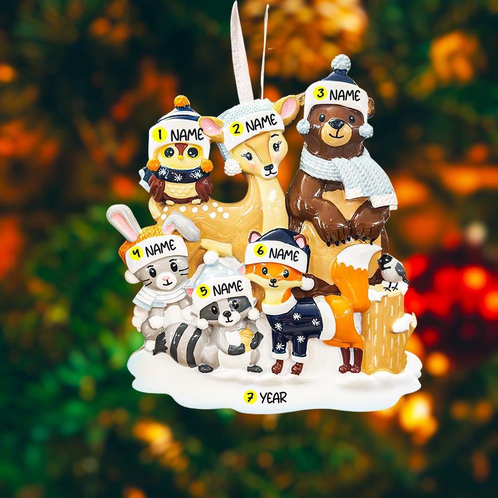 Decorative ornament with cartoon animals wearing hats and scarves on a blurred Christmas tree background.