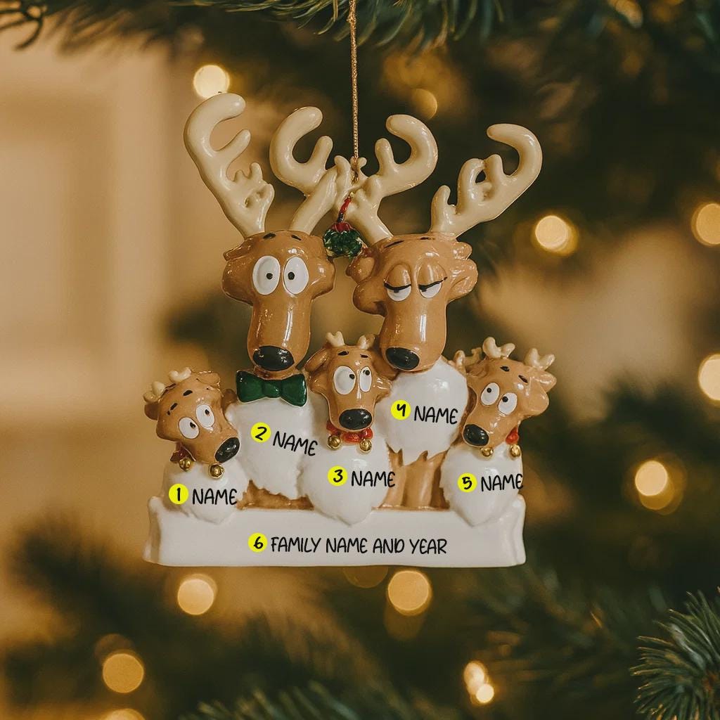 Personalized reindeer family ornament on a Christmas tree with blurred lights in the background.