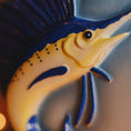 Load image into Gallery viewer, Close-up of a yellow Sailfish figurine with blue accents on a textured surface.
