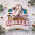 Load image into Gallery viewer, Personalized ballet Christmas ornament featuring soft pink ballet shoes with delicate ribbon details and a glittered ballet banner, customizable name area on the lower front ribbon and customizable year area beside the name, glossy finish with raised 3D front elements and flat 2D back, white hanging ribbon, displayed on a warm snowy holiday background with festive greenery ornaments and cozy Christmas decor.
