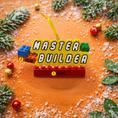 Load image into Gallery viewer, Personalized Master Builder Christmas ornament featuring a raised 3D front with colorful building block design and bold lettering. The ornament has a flat 2D back for easy hanging and durability. Bright primary colors and playful block details make it perfect for kids who love building toys. Personalization includes name and year, added by hand, making it a fun and meaningful holiday keepsake for children and young builders.
