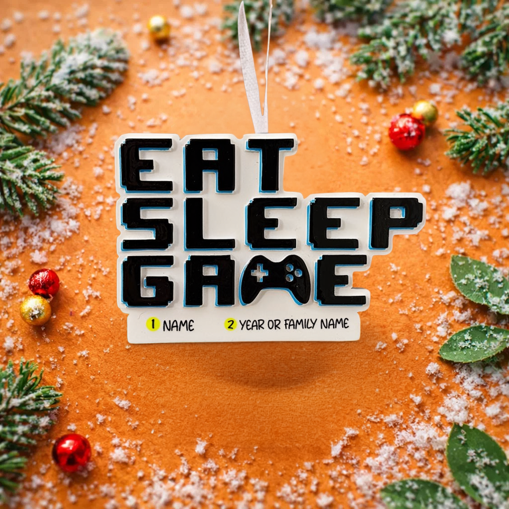 Personalized Eat Sleep Game Christmas ornament with a raised 3D front featuring bold block-style lettering and a detailed game controller icon. The front design is fully three dimensional, creating depth and texture, while the back is flat 2D for easy hanging and durability. White base with black raised letters and subtle colored accents. Includes hand-added personalization with name and year or family name. Gaming-themed holiday ornament displayed on snowy festive background with warm lights, designed for 