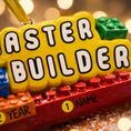 Load image into Gallery viewer, Personalized Master Builder Christmas ornament featuring a raised 3D front with colorful building block design and bold lettering. The ornament has a flat 2D back for easy hanging and durability. Bright primary colors and playful block details make it perfect for kids who love building toys. Personalization includes name and year, added by hand, making it a fun and meaningful holiday keepsake for children and young builders.

