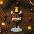 Load image into Gallery viewer, Decorative Christmas ornament resembling a street lamp with festive elements on a wooden surface.
