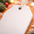 Load image into Gallery viewer, White tag with customizable ornament text on a festive background with Christmas decorations
