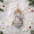 Load image into Gallery viewer, Angel ornament with a heart on a snowy background with Christmas decorations
