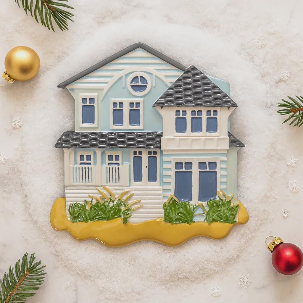 Decorative house ornament on a textured surface with Christmas decorations.
