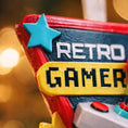 Load image into Gallery viewer, Personalized retro gamer Christmas ornament featuring a classic arcade style joystick and bold gaming icons. Raised 3D front details create depth while the back remains flat for easy hanging. Custom name and year placement make this ornament a fun and nostalgic keepsake for gamers and holiday tree decor.
