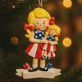 Load image into Gallery viewer, Decorative Christmas ornament of two girls in American flag dresses against a blurred Christmas tree background.
