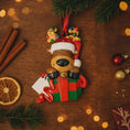 Load image into Gallery viewer, Christmas ornament of a reindeer in a gift with lights on a wooden surface with decorations.
