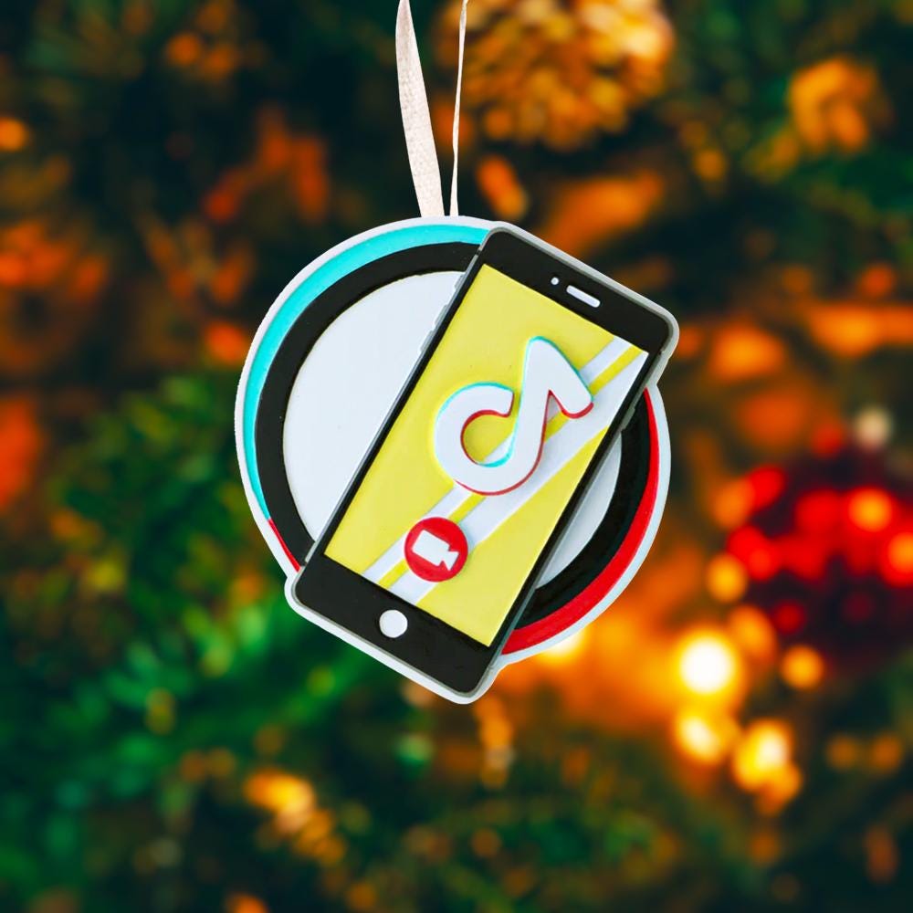Decorative ornament with smartphone and music app icon on a blurred Christmas tree background