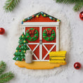 Load image into Gallery viewer, Decorative Christmas scene with a red barn, wreaths, a tree, and a lantern on a snowy background.
