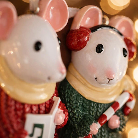 Two decorative mouse figurines with festive attire and a candy cane against a blurred light background.